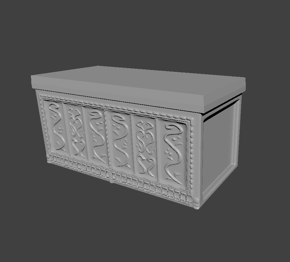 A grey image of a 3D model chest with an elaborately decorated front. It stands in free, grey space. 